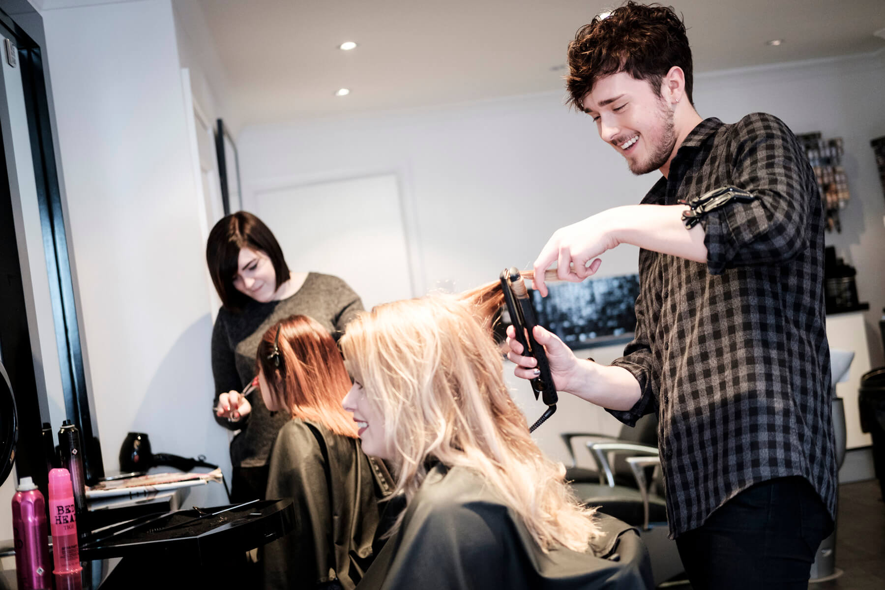 Two people in a salon doing two other people's hair