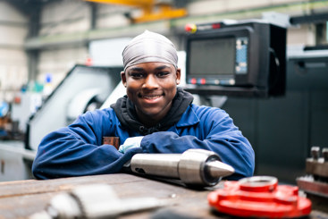 Young male student stood in front of engineering equipment
