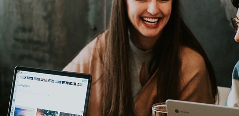 A person smiling and working with colleagues sat around a desk
