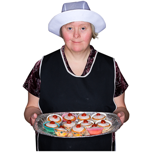 A lady wearing a pinafore and hat holding a tray of cupcakes.