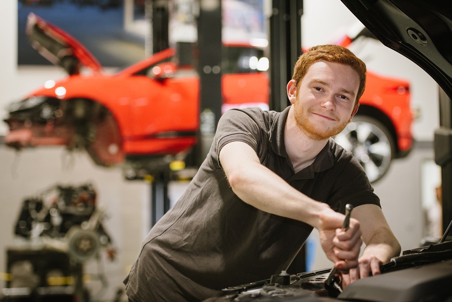 Apprentice from Carrs Jaguar in a car workshop fixing a car 