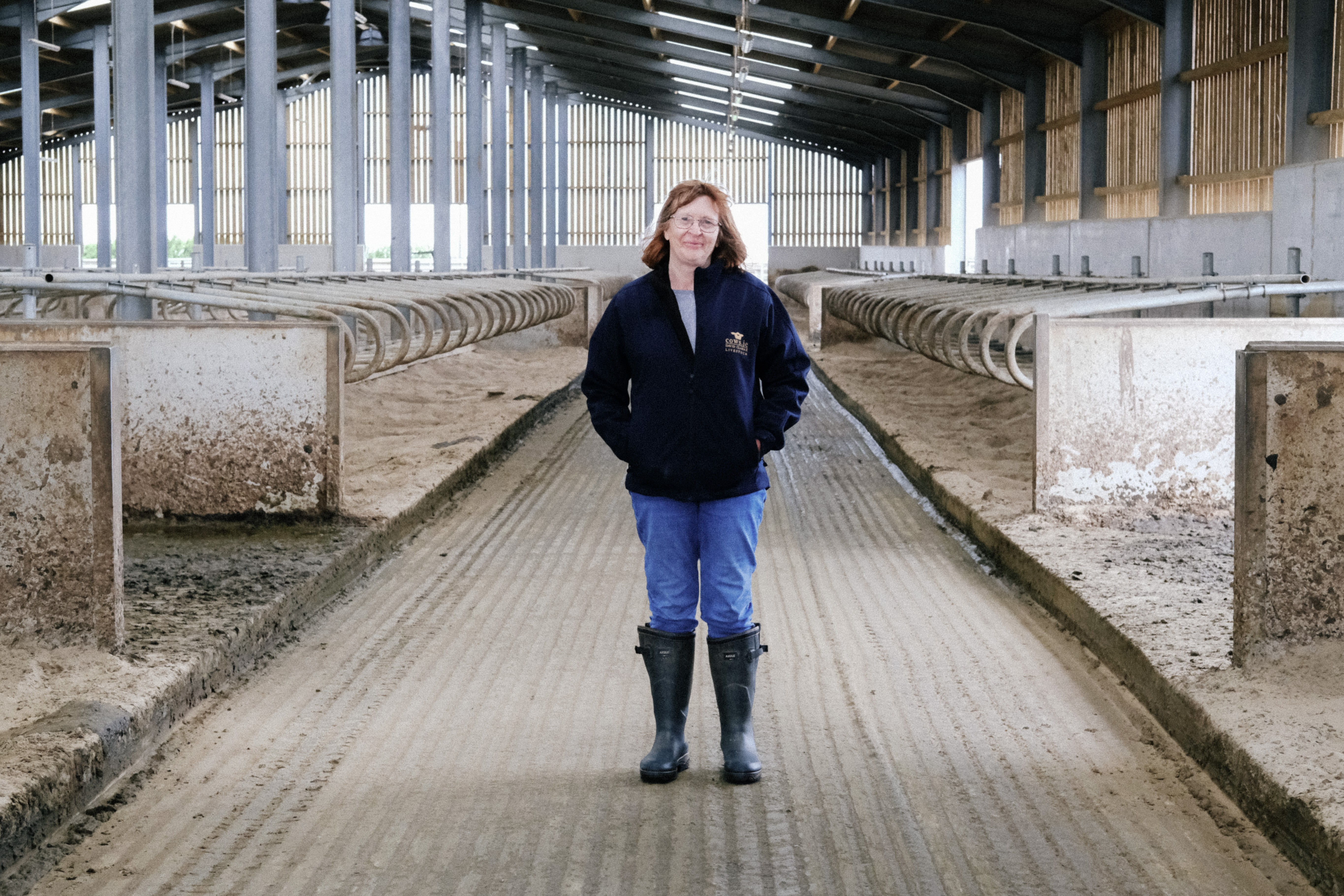 Farmer stood in empty cow barn