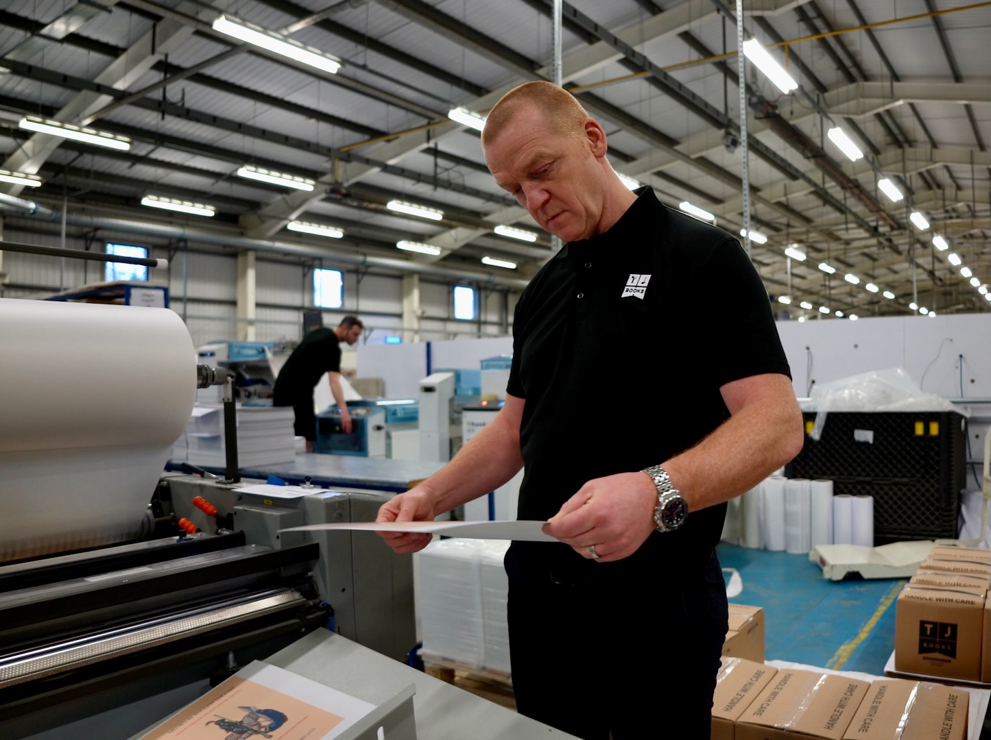 Person stood in a print factory checking printouts