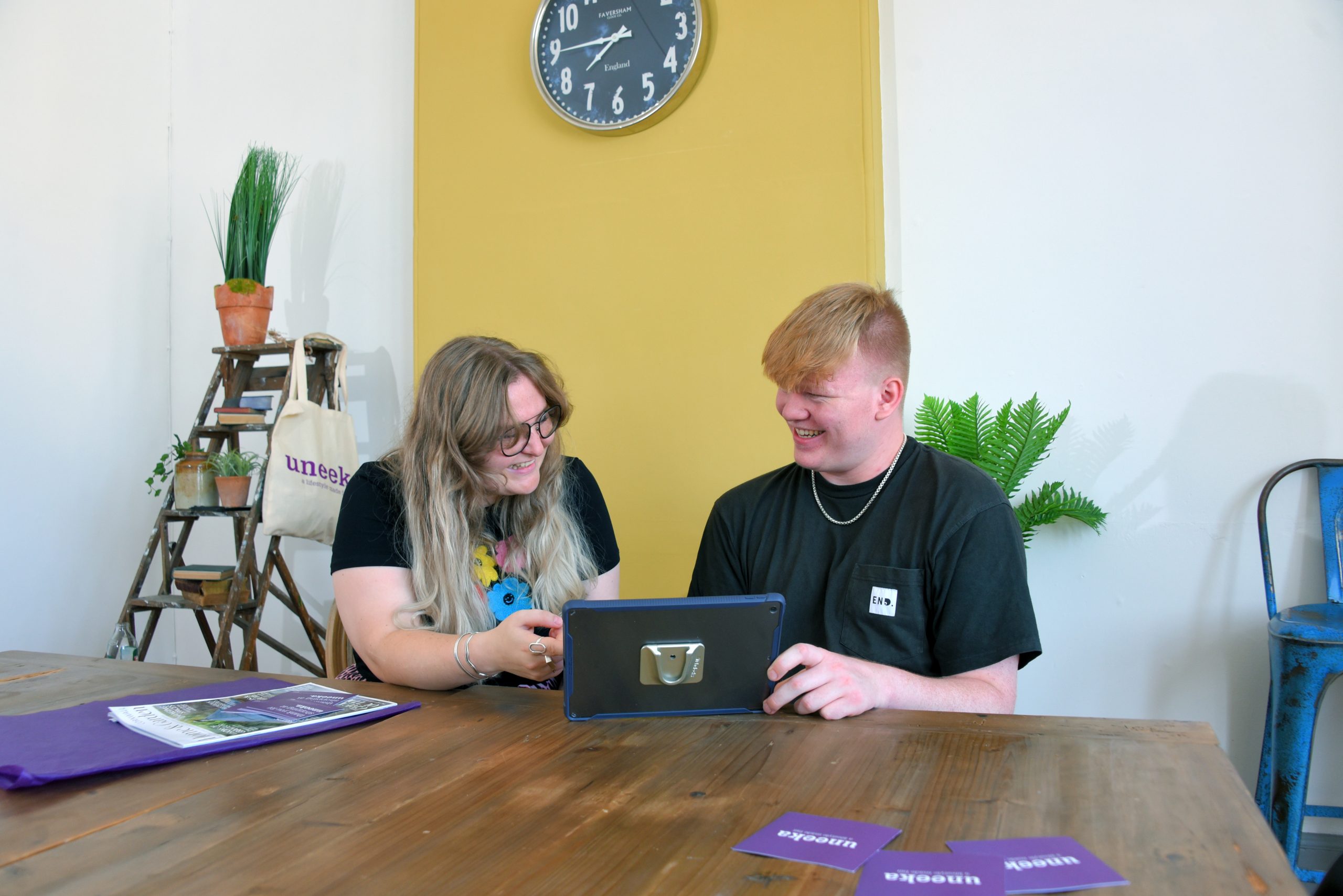 Two people talking over a tablet sat at a table