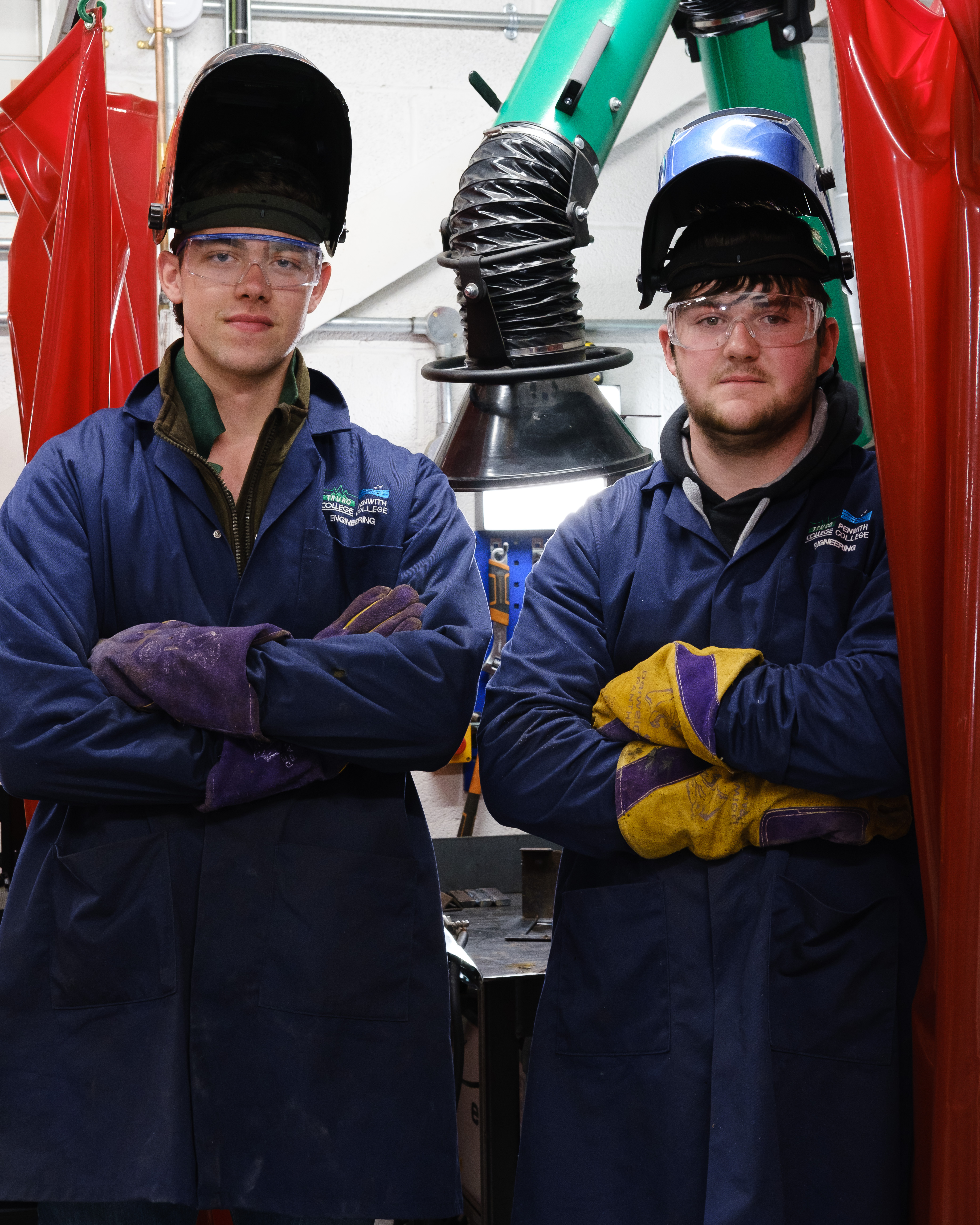 Students stood with arms crossed wearing welding helmets